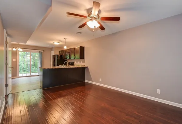 a living room with stainless steel appliances kitchen island hardwood floor and a window