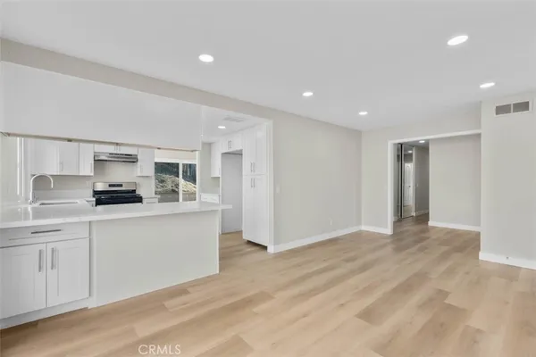 a large white kitchen with stainless steel appliances granite countertop a sink and cabinets