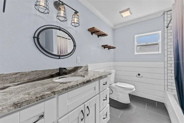 a bathroom with a granite countertop toilet a sink and a mirror