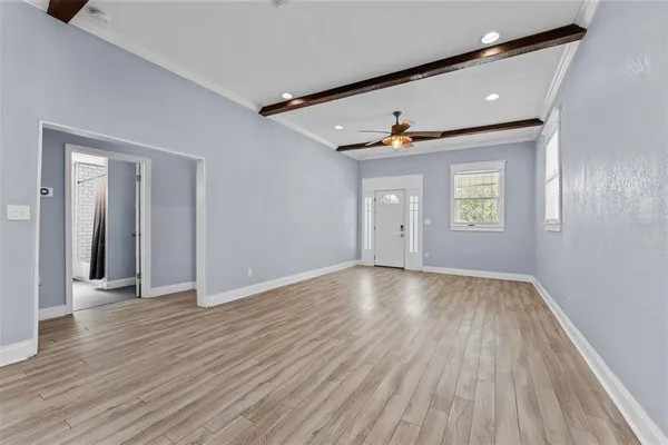 a view of an empty room with wooden floor and a window