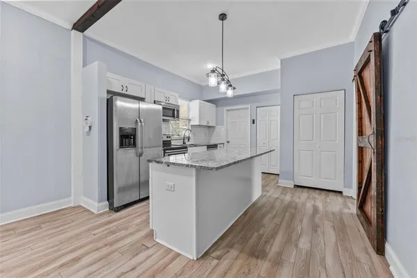 a kitchen with stainless steel appliances granite countertop a refrigerator a sink dishwasher a stove and white countertops with wooden floor
