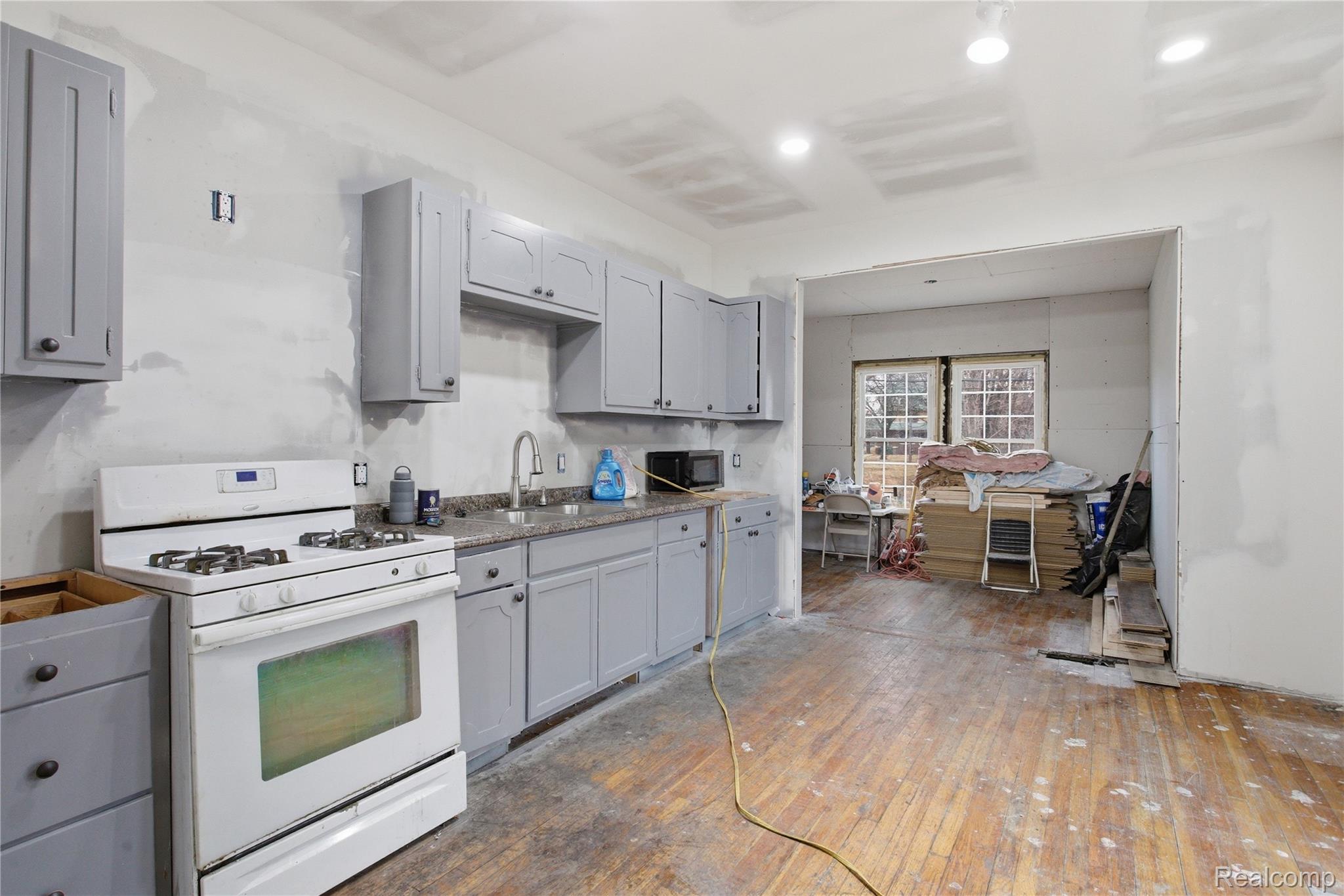 4624 Pacific Street Detroit, MI 48204 - Photo 12 of 39 Kitchen with gray cabinets, white gas range, hardwood / wood-style flooring, and stainless steel microwave