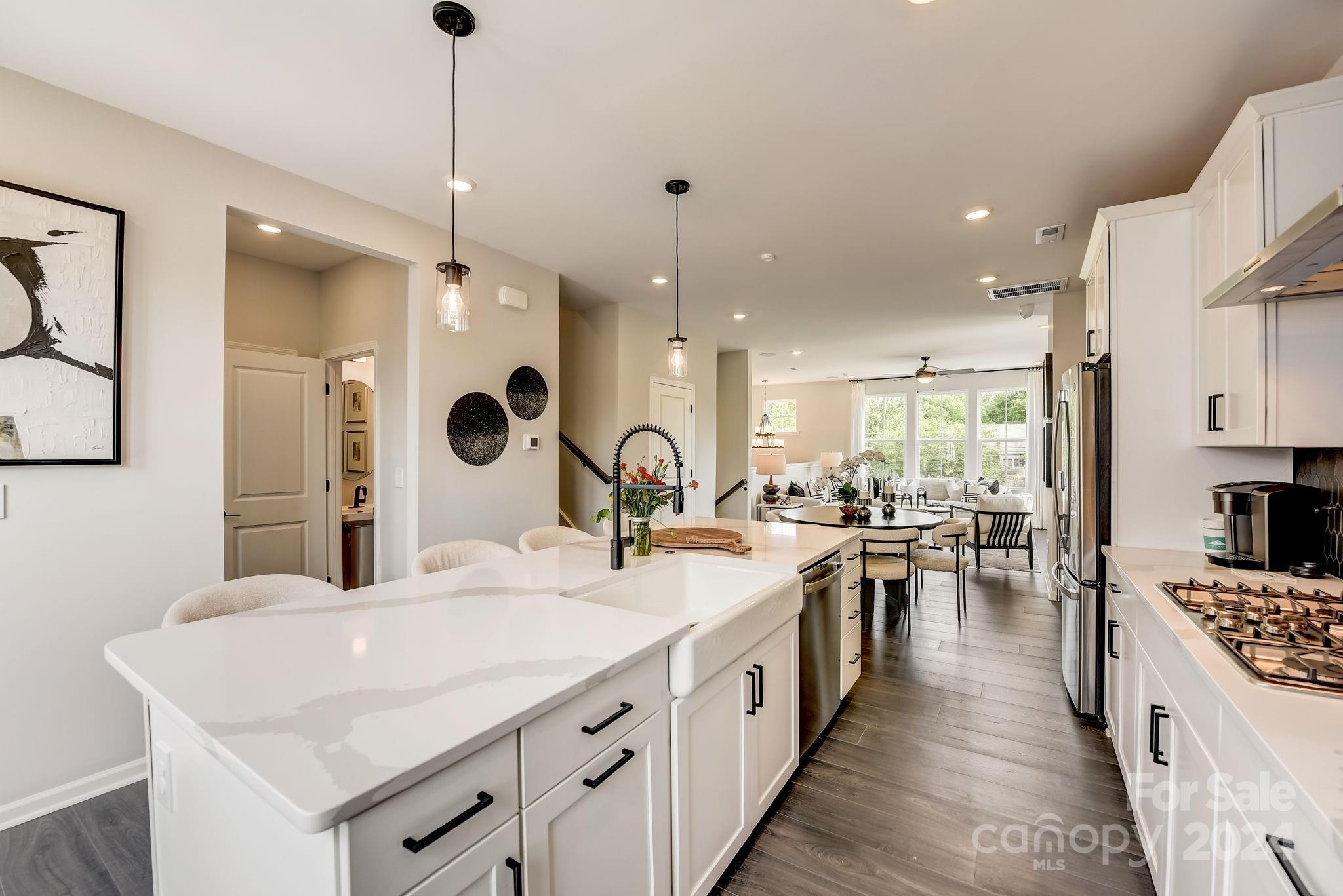 109 Goodson Place Davidson, NC 28036 - Photo 21 of 40 a large kitchen with kitchen island a stove a sink a oven and a dining table with wooden floor