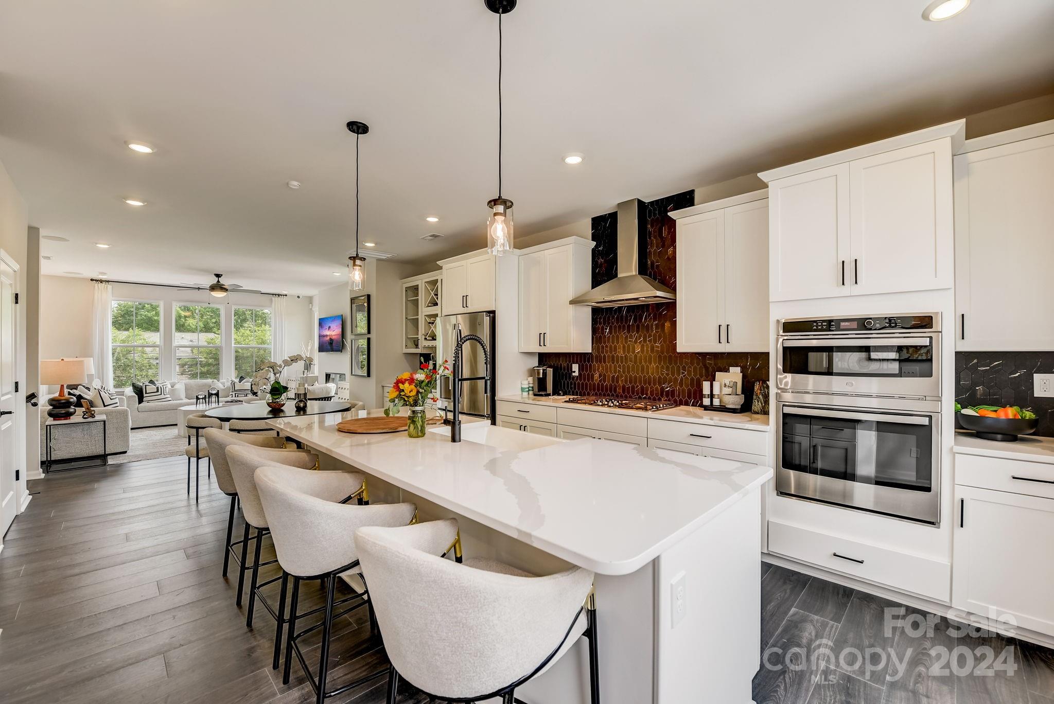 109 Goodson Place Davidson, NC 28036 - Photo 22 of 40 a kitchen with stainless steel appliances kitchen island granite countertop a stove a sink a microwave a dining table and chairs with wooden floor