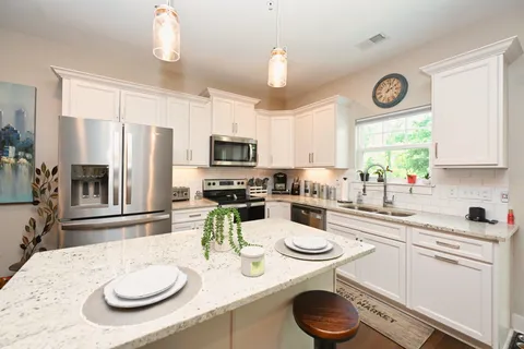 a kitchen with sink a stove and white table with chairs