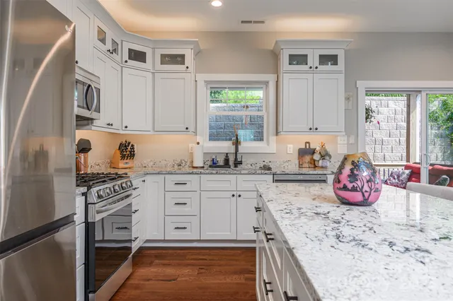 a kitchen with granite countertop a sink cabinets stainless steel appliances and windows