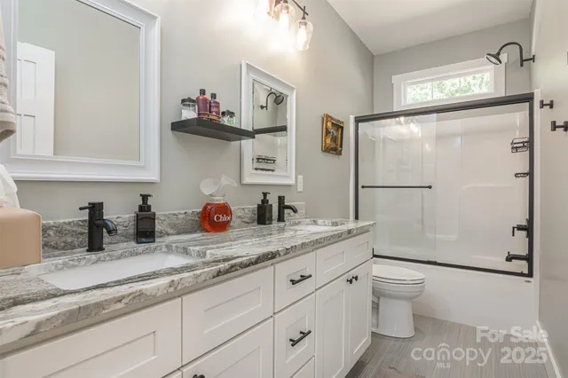 a bathroom with a granite countertop sink a toilet and a shower
