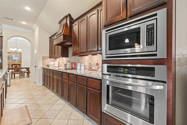 a dining room filled a chandelier and kitchen view