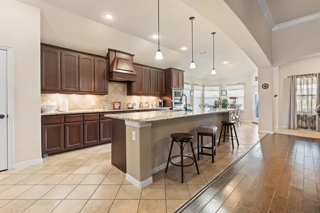 a kitchen with kitchen island a dining table chairs stainless steel appliances and cabinets
