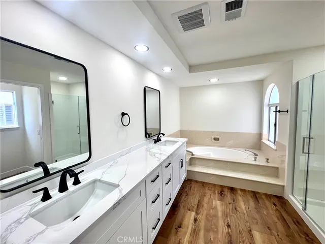 a bathroom with a double vanity sink and mirror with bathtub