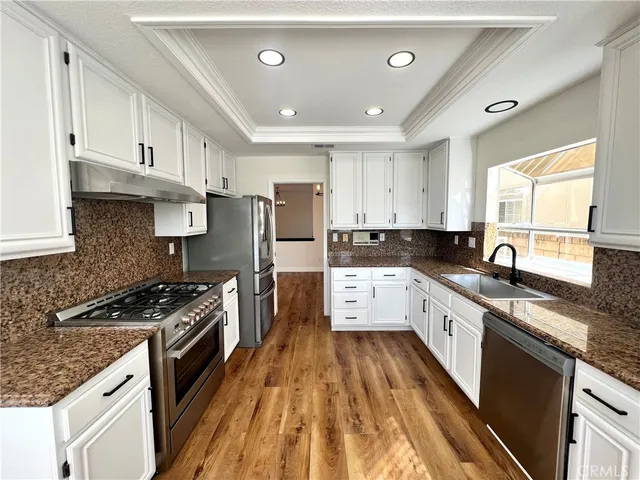 a large kitchen with stainless steel appliances granite countertop a stove a sink dishwasher and a refrigerator