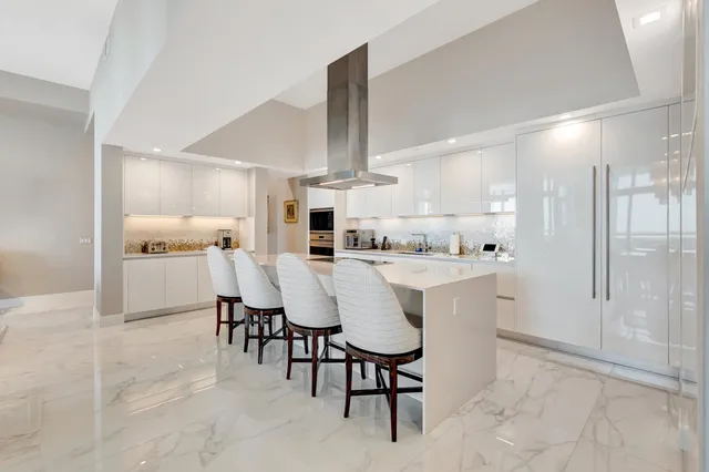 a kitchen with kitchen island a dining table chairs stainless steel appliances and cabinets