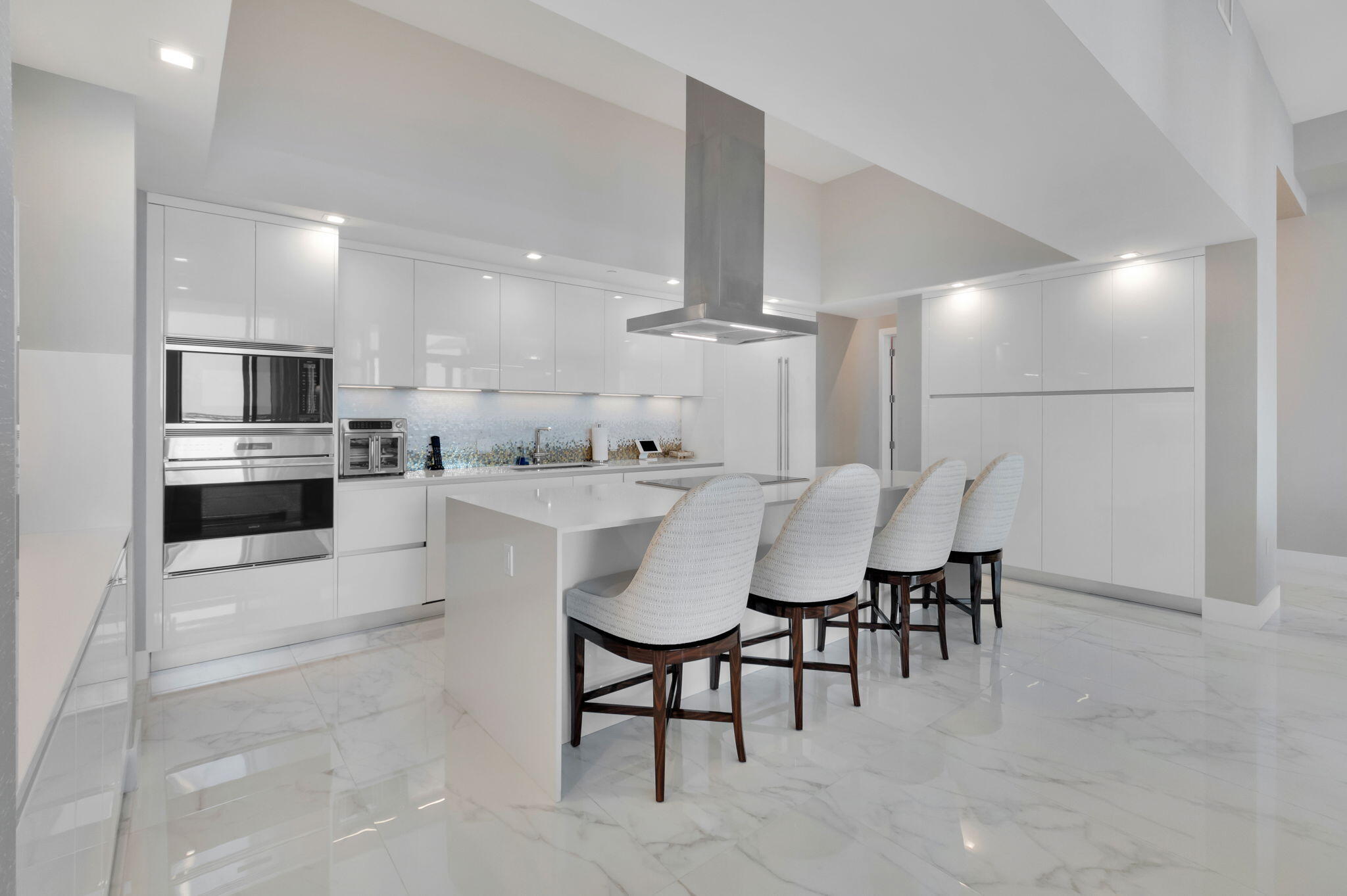 20155 Boca W Drive, Unit PHC902 Boca Raton, FL 33434 - Photo 10 of 56 a kitchen with kitchen island a dining table chairs stainless steel appliances and cabinets