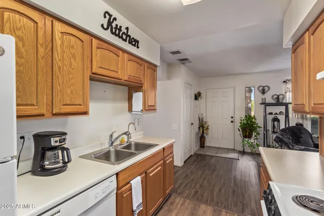 a kitchen with stainless steel appliances granite countertop a sink dishwasher stove and refrigerator with wooden floor