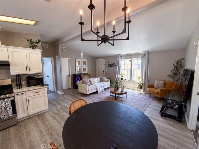 a living room with furniture kitchen view and a wooden floor