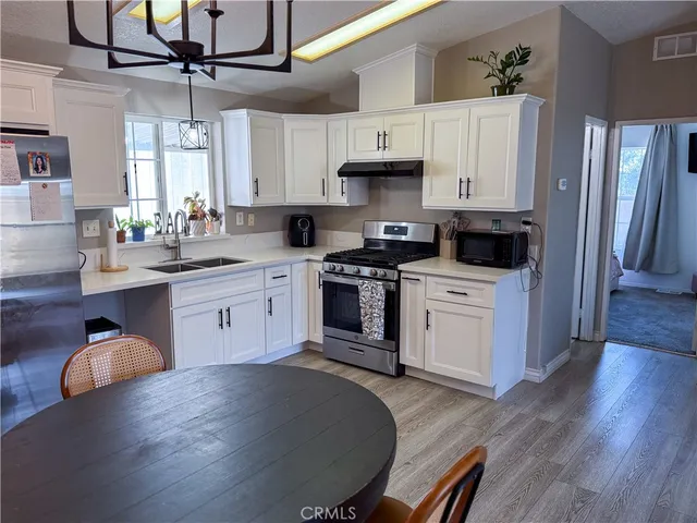 a kitchen with stainless steel appliances granite countertop a stove a sink dishwasher and a refrigerator with wooden floor