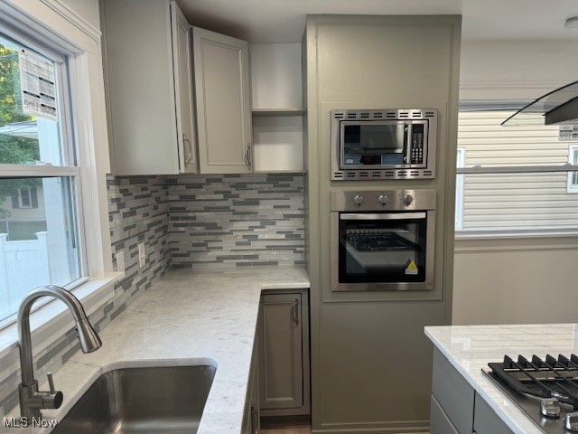 18210 Windward Road Cleveland, OH 44119 - Photo 30 of 40 Kitchen with backsplash, gray cabinetry, sink, and stainless steel appliances