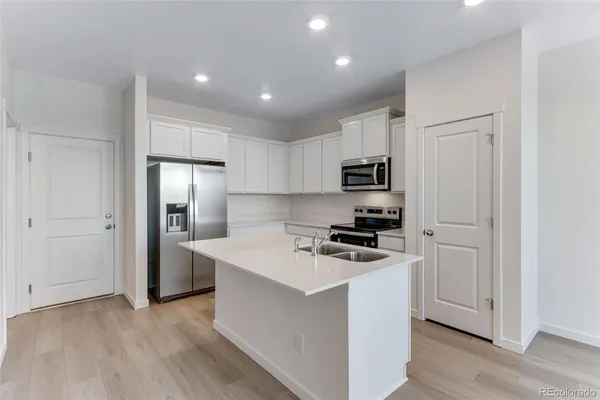 a kitchen with cabinets stainless steel appliances and wooden floor