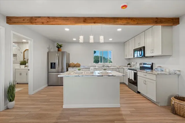 a view of a kitchen with kitchen island a stove a sink dishwasher and a refrigerator with wooden floor