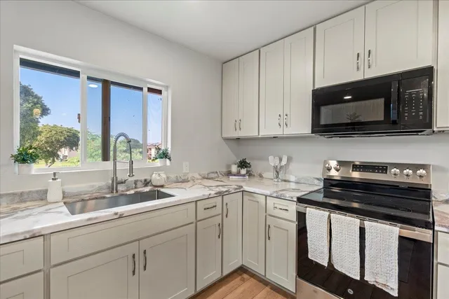 a kitchen with stainless steel appliances granite countertop white cabinets a sink and dishwasher next to a window