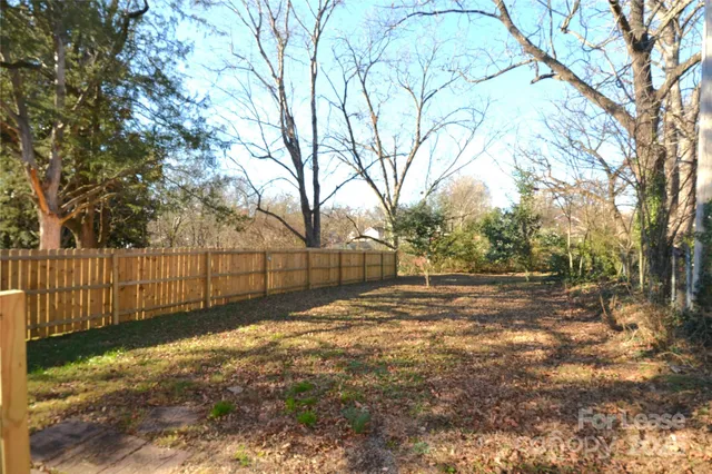 a view of a yard with wooden fence and trees