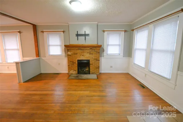 a view of empty room with wooden floor and fireplace