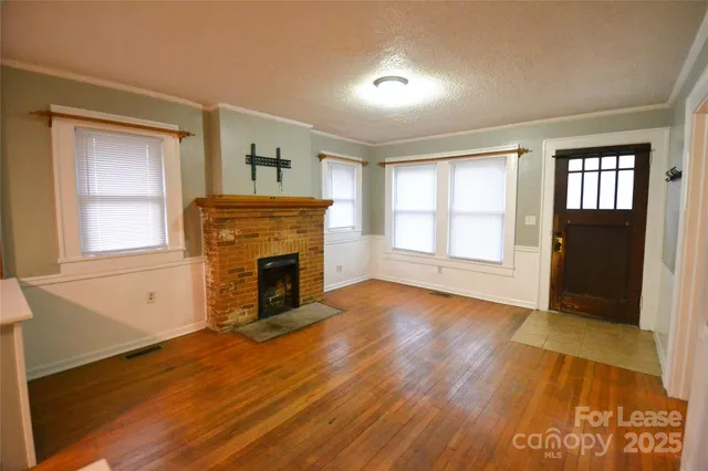 an empty room with windows fireplace and wooden floor