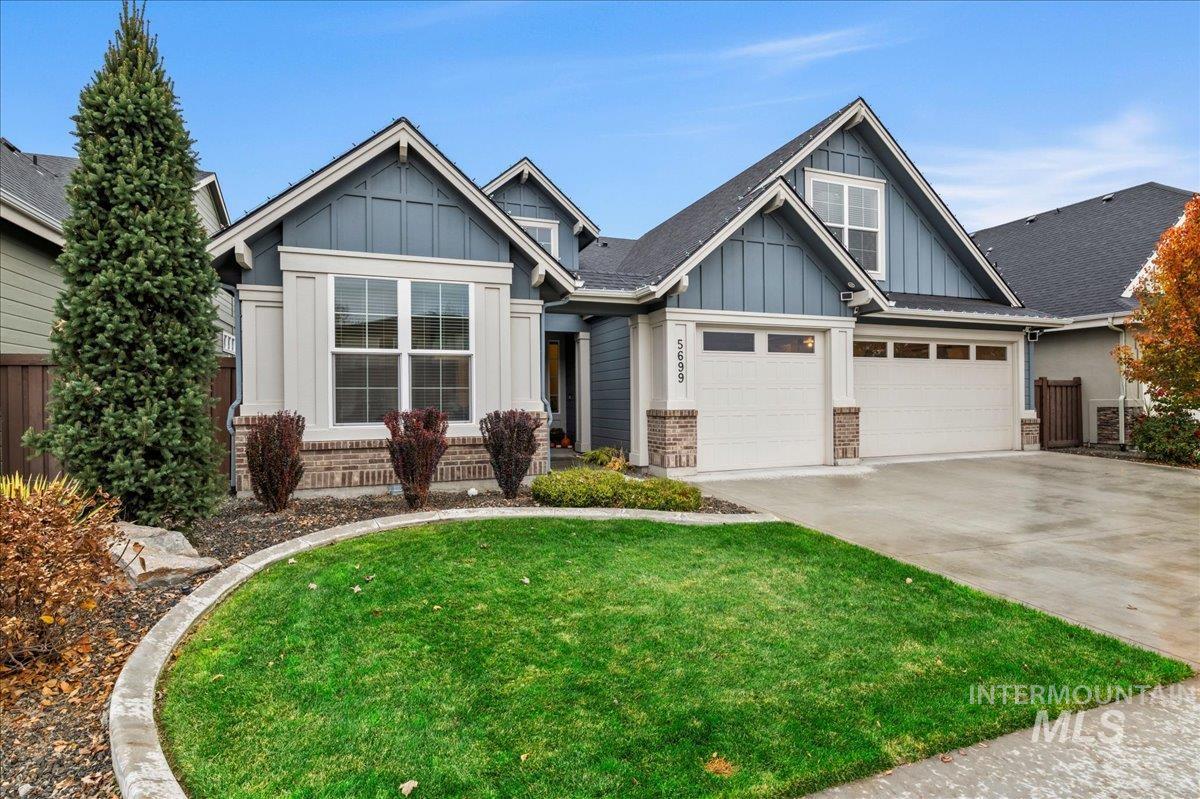 Craftsman-style house featuring board and batten siding, brick siding, driveway, and an attached garage