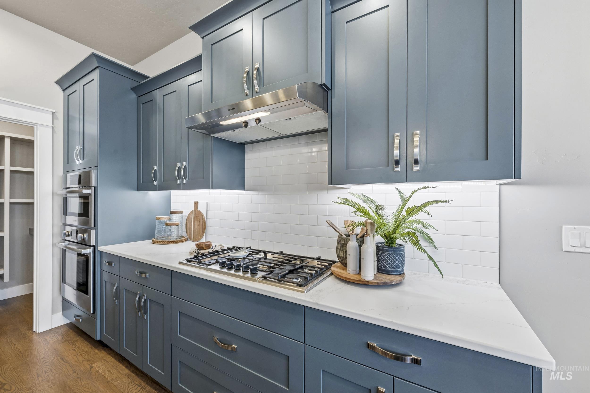 5699 North Fairborn Avenue Meridian, ID 83646 - Photo 12 of 30 Kitchen featuring stainless steel appliances, light stone countertops, dark wood-style flooring, and backsplash