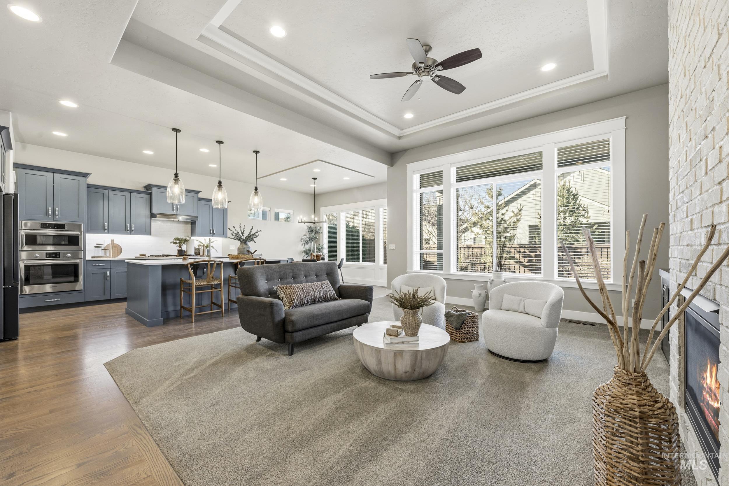 5699 North Fairborn Avenue Meridian, ID 83646 - Photo 5 of 30 Living room featuring a ceiling fan, a fireplace, a tray ceiling, recessed lighting, and dark wood-type flooring