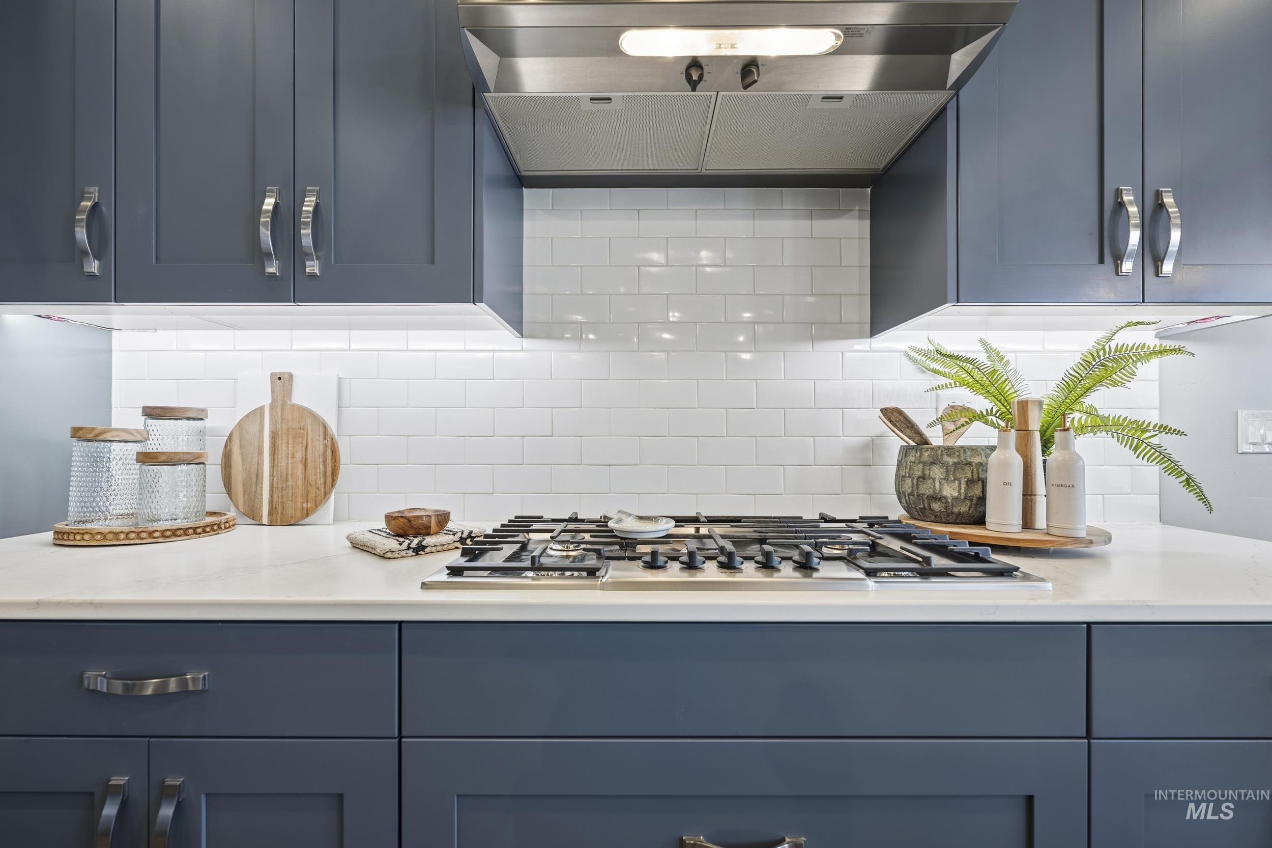 5699 North Fairborn Avenue Meridian, ID 83646 - Photo 6 of 30 Kitchen with blue cabinetry, stainless steel gas cooktop, backsplash, and light stone countertops