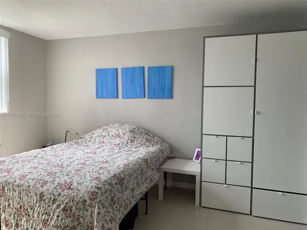 a bedroom with a bed and a refrigerator