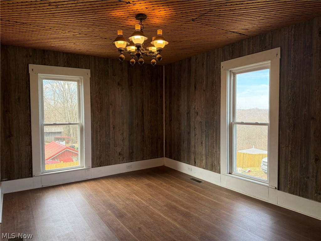23033 Cadiz Road Freeport, OH 43973 - Photo 22 of 31 Spare room featuring wood finished floors, a chandelier, wood ceiling, wooden walls, and plenty of natural light