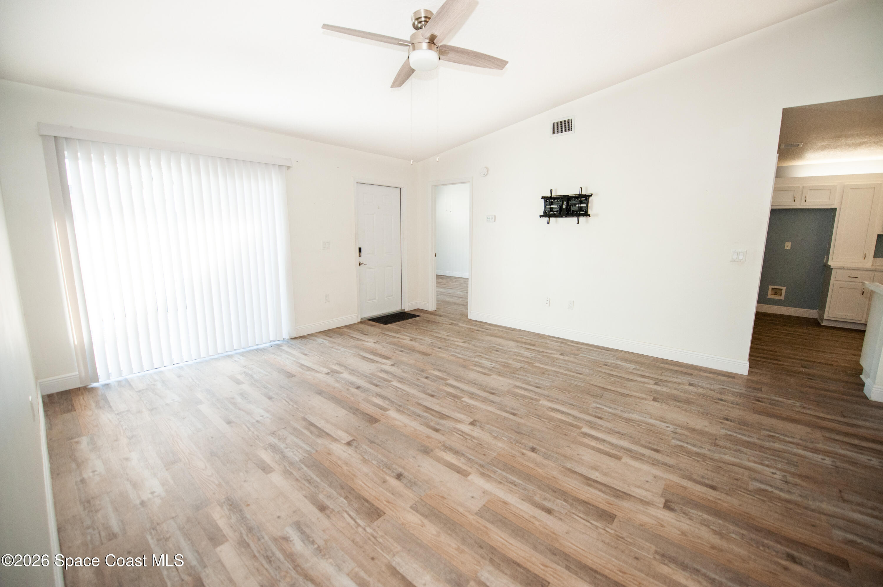 1942 Quail Ridge Court, Unit 504 Cocoa, FL 32926 - Photo 5 of 27 an empty room with wooden floor and windows