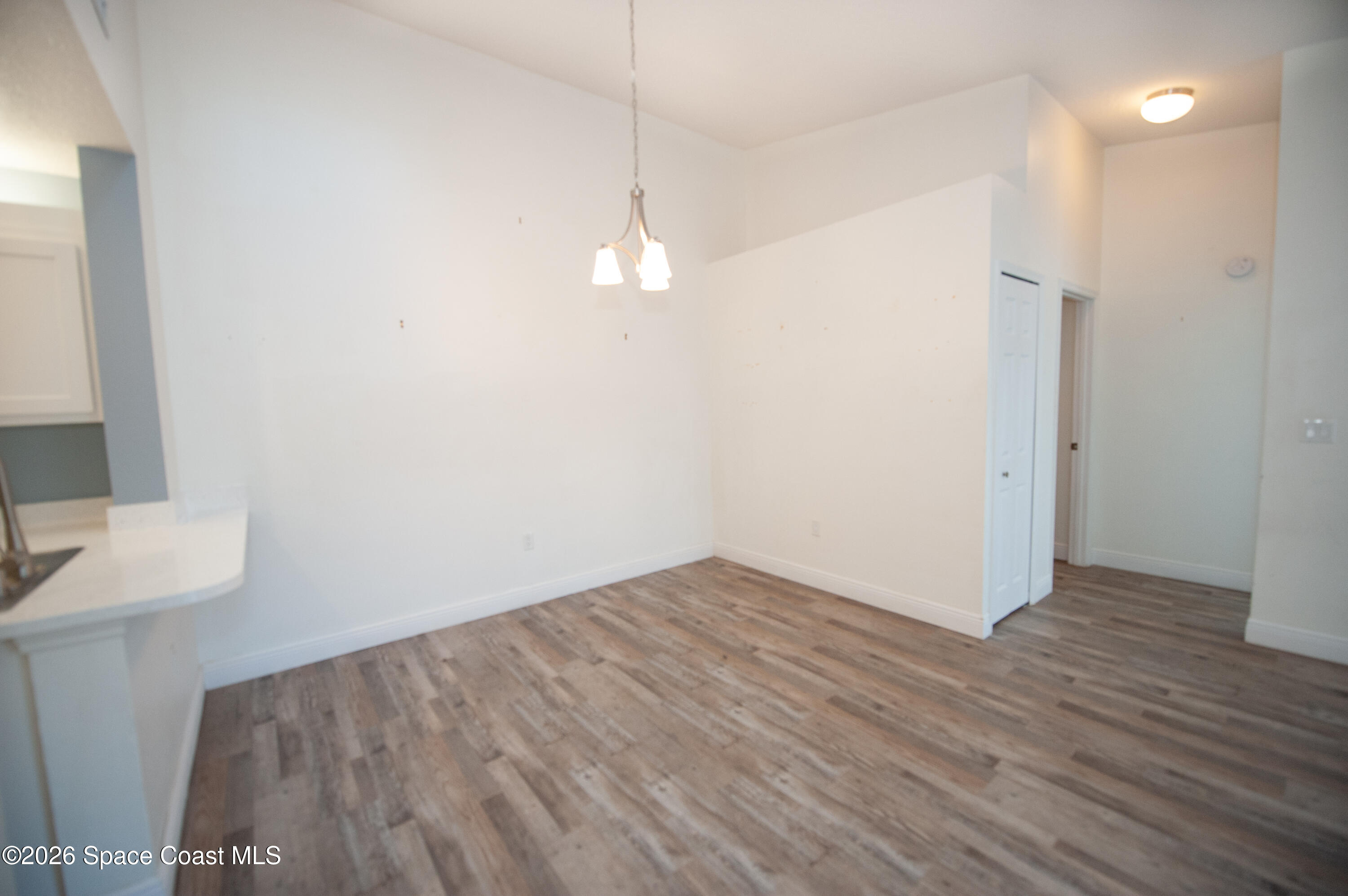 1942 Quail Ridge Court, Unit 504 Cocoa, FL 32926 - Photo 6 of 27 an empty room with wooden floor and windows