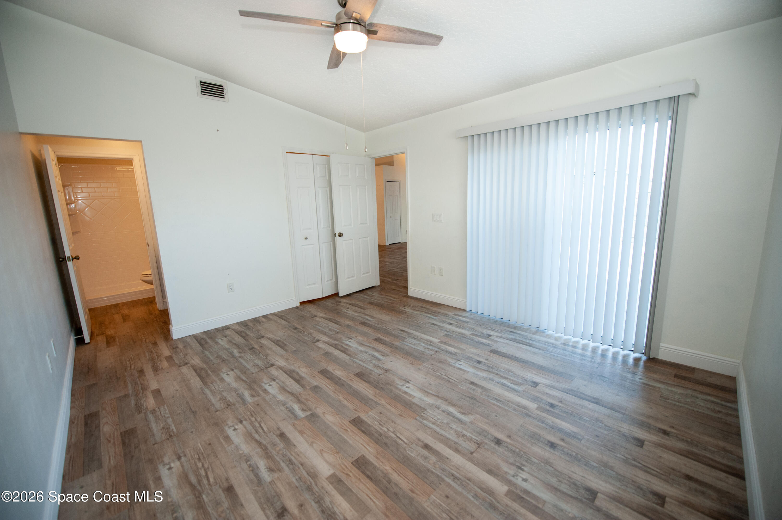 1942 Quail Ridge Court, Unit 504 Cocoa, FL 32926 - Photo 8 of 27 an empty room with wooden floor and a ceiling fan
