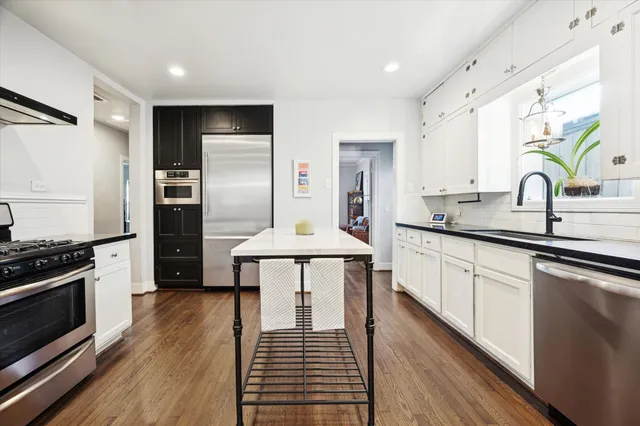 a kitchen with stainless steel appliances a stove a sink dishwasher a refrigerator and cabinets with wooden floor