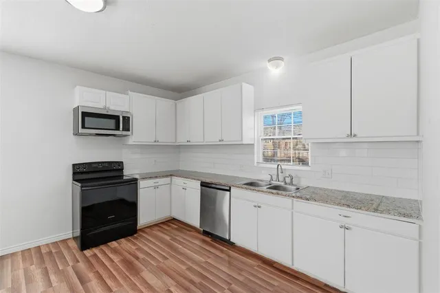 a kitchen with granite countertop a sink stainless steel appliances and white cabinets