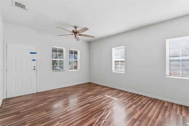 a view of empty room with wooden floor and fan