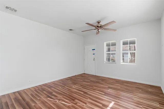 a view of a room with wooden floor and a ceiling fan