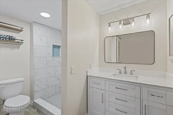 a bathroom with a granite countertop toilet sink and mirror