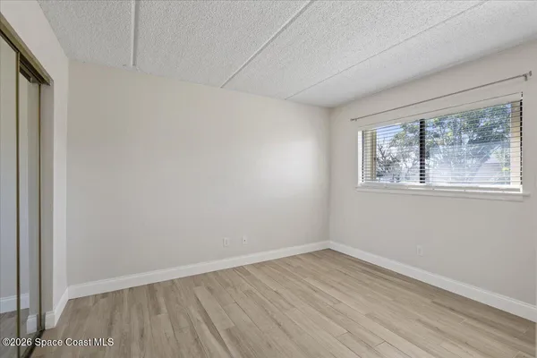 a view of empty room with wooden floor and fan