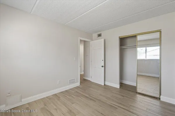 a view of an empty room with wooden floor and closet