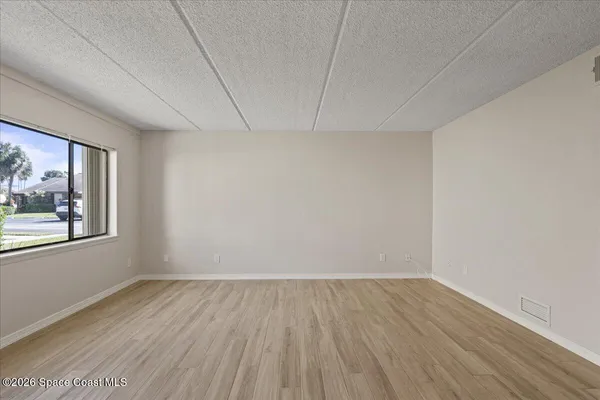 a view of empty room with wooden floor and fan