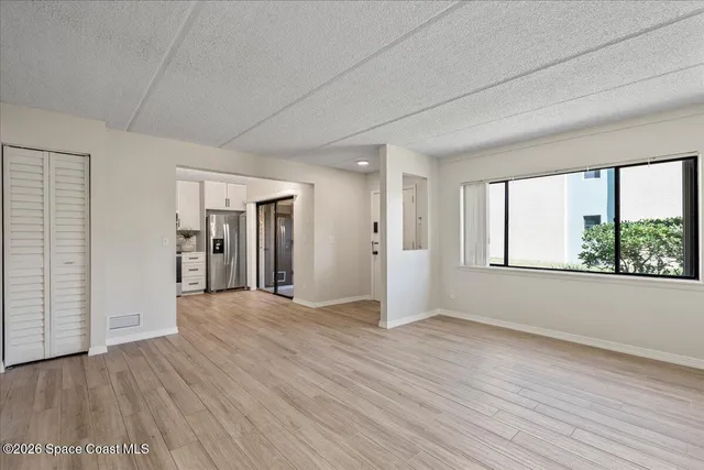 a view of an empty room with window and wooden floor
