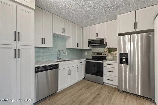 a kitchen with granite countertop a refrigerator stove and white cabinets