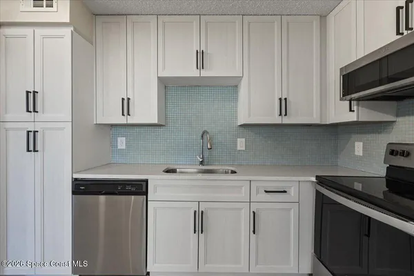 a kitchen with white cabinets and a stove with a sink