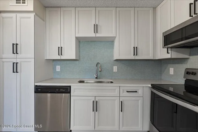 a kitchen with white cabinets and a stove with a sink