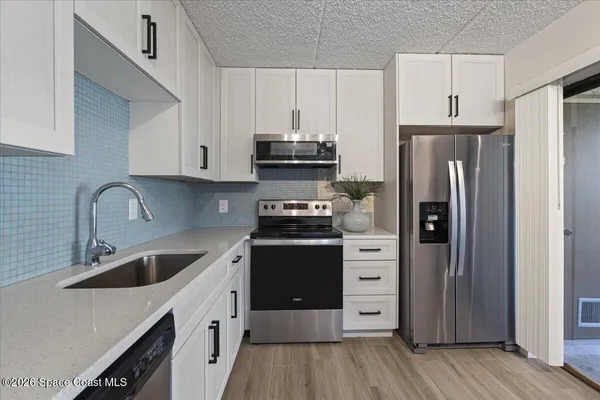 a kitchen with a refrigerator sink and cabinets