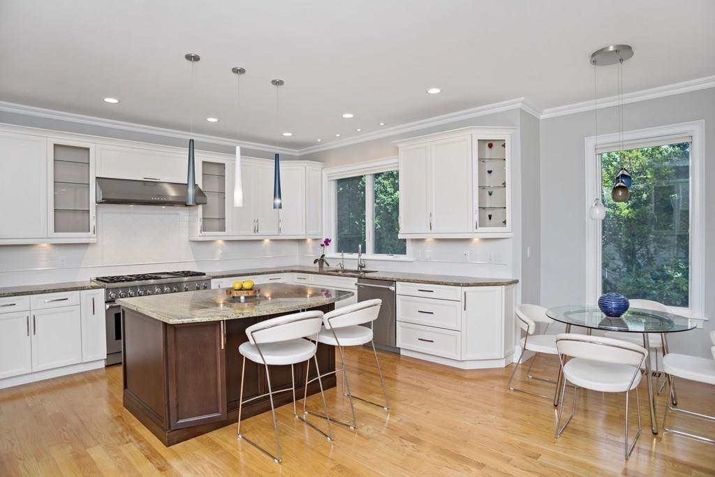 34 Dorothy Road Newton, MA 02459 - Photo 3 of 41 a kitchen with a stove a sink a kitchen island with chairs and wooden cabinets
